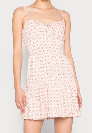 Robe fleurie blanche avec motifs de fleurs orange, dotée de fines bretelles, d'un décolleté en cœur et d'un ourlet volanté. Tissu léger.