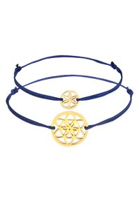 Charms de metal en tono dorado con intrincados diseños florales en un cordón azul marino. Presenta dos tamaños: charm pequeño en forma de círculo y charm grande en forma redonda.