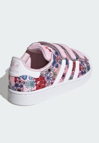 Rožnate superge z cvetličnim vzorcem in belimi poudarki, ki imajo tri bele črte in zapiranje z ježkom. Podložena notranjost in gumijast podplat z vzorcem.