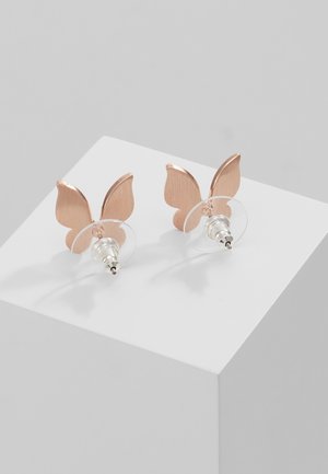 Orecchini a bottone a forma di farfalla in oro rosa con chiusure in plastica trasparente esposti su un piedistallo cubico bianco.