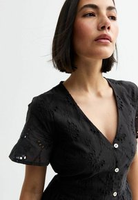 Black dress featuring floral embroidery, short sleeves, a V-neck, and button closures. Made from textured fabric with a fitted silhouette.