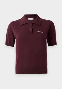 Bordo polo majica s kratkim rukavima s rebrastim ovratnikom i rubom, koja sadrži dva gumba i izvezenu oznaku "2ND DAY" na lijevoj strani prsiju.