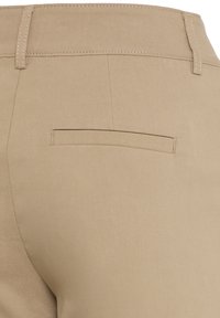 Bež hlače z gladkim tekstilom, ravnim krojem in eno zadnjo žep s horizontalnim odprtjem.