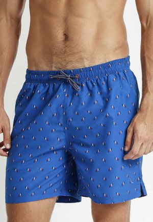 Bañadores azules con cintura elástica y cordón. Presentan un patrón de pequeñas banderas diagonales rojas, blancas y azules en todo el tejido.