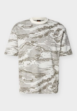 Κοντομάνικο T-shirt με στρογγυλή λαιμόκοψη και αφαίρετο μοτίβο καμουφλάζ σε μπεζ και λευκό, εμφανιζόμενο σε απλό φόντο.