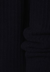 Marinblå stickad tröja med ribbat mönster. Har uppvikt manschett och vertikala ränder, tillverkad av mjukt, elastiskt material för komfort.