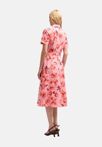 Rochie midi florală din țesătură roz, cu mâneci scurte, guler și talie ajustată. Model proeminent cu flori roșii și portocalii pe întreaga suprafață.