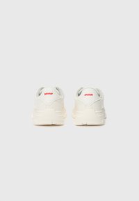 Adidași albi cu un sistem superior din piele netedă, accente gri și o talpă texturată. Prezintă un logo roșu la călcâi și un design rotunjit, cu amortizare.