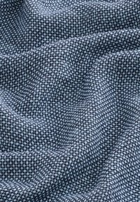 Tkanina teksture u nijansama tamnoplave i svijetloplave, s uzorkom na kockice koji sadrži fine, kontrastne niti utkane u mekan, blago naboran završetak.