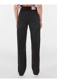 Svarta raka jeans med hög midja, två bakfickor och ett strukturerat tyg med subtila variationer.