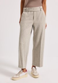 Světle šedé tailored kalhoty s texturovanou tkaninou, širokými nohavicemi, vysokým pasem a předními kapsami, spárované s béžovými a růžovými teniskami.