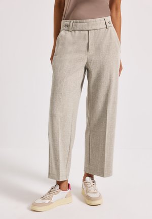 Hellgraue, maßgeschneiderte Hose aus strukturiertem Stoff mit weitem Bein, hoher Taille und Gesäßtaschen, kombiniert mit beigen und rosa Sneakern.