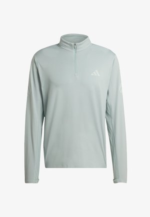 Světlounce šedý atletický pulovr s dlouhým rukávem, čtvrtinovým zipem a jemným logem Adidas na hrudi a rukávech, pohled zepředu.