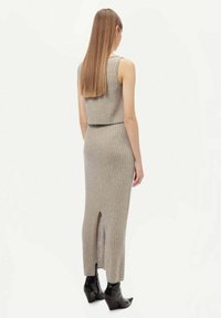 Grå ribbad stickad tvådelad klänning med en kortärmad topp och en lång kjol med en slits bak, kombinerad med svarta ankelboots.