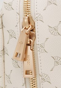 Krémová kabelka s raženým květinovým vzorem, vybavená zlatým zipem se dvěma jezdci, rytým logem a hladkým texturovaným povrchem.
