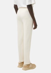 Crème-kleurige sweatpants van zacht materiaal met een elastische tailleband, in combinatie met tan sneakers met textuuraccenten.