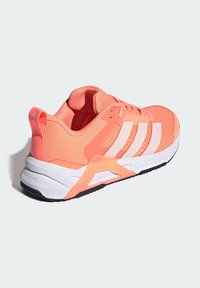 Coral athletic shoe with white three stripes. Mesh upper, padded collar, and contrasting white and black sole. Features a textured finish.