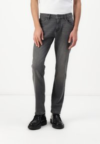 Vaqueros de denim gris con corte ajustado, cinco bolsillos y un ligero desvanecimiento. Combinados con botas negras de cordones. Diseño simple y limpio.