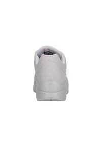 Sneakers atletici bianchi con una tomaia liscia simile alla pelle, colletto imbottito e suola testurizzata. Presentano un logo sul tallone e accenti perforati.
