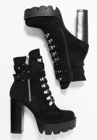 Bottines en suede noir avec une plateforme épaisse et un talon haut, dotées de matériel en acier inoxydable, de lacets et de fermetures éclair latérales. Semelle plate et texturée.