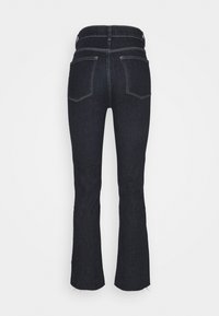 Jeans de denim oscuro acampanados con cintura alta, diseño de cuatro bolsillos, costuras en contraste y ligero deshilachado en el dobladillo.