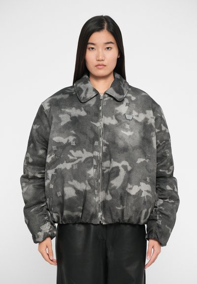 Veste matelassée à motif camouflage gris, dotée d'un col à pression, d'une fermeture éclair frontale et d'un ourlet côtelé. Texture douce avec des accents de marque subtils.
