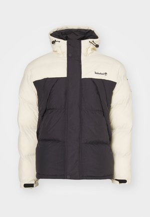 Veste rembourrée avec un haut crème et un bas gris foncé, dotée d'un col haut, d'une capuche ajustable et de poches avant. Logo sur la zone de la poitrine.