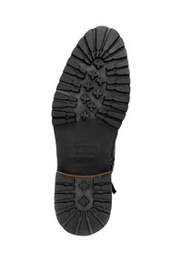 Suela de bota de goma negra con dibujos profundos para tracción, un logo rectangular en relieve y un acabado texturizado con líneas definidas.