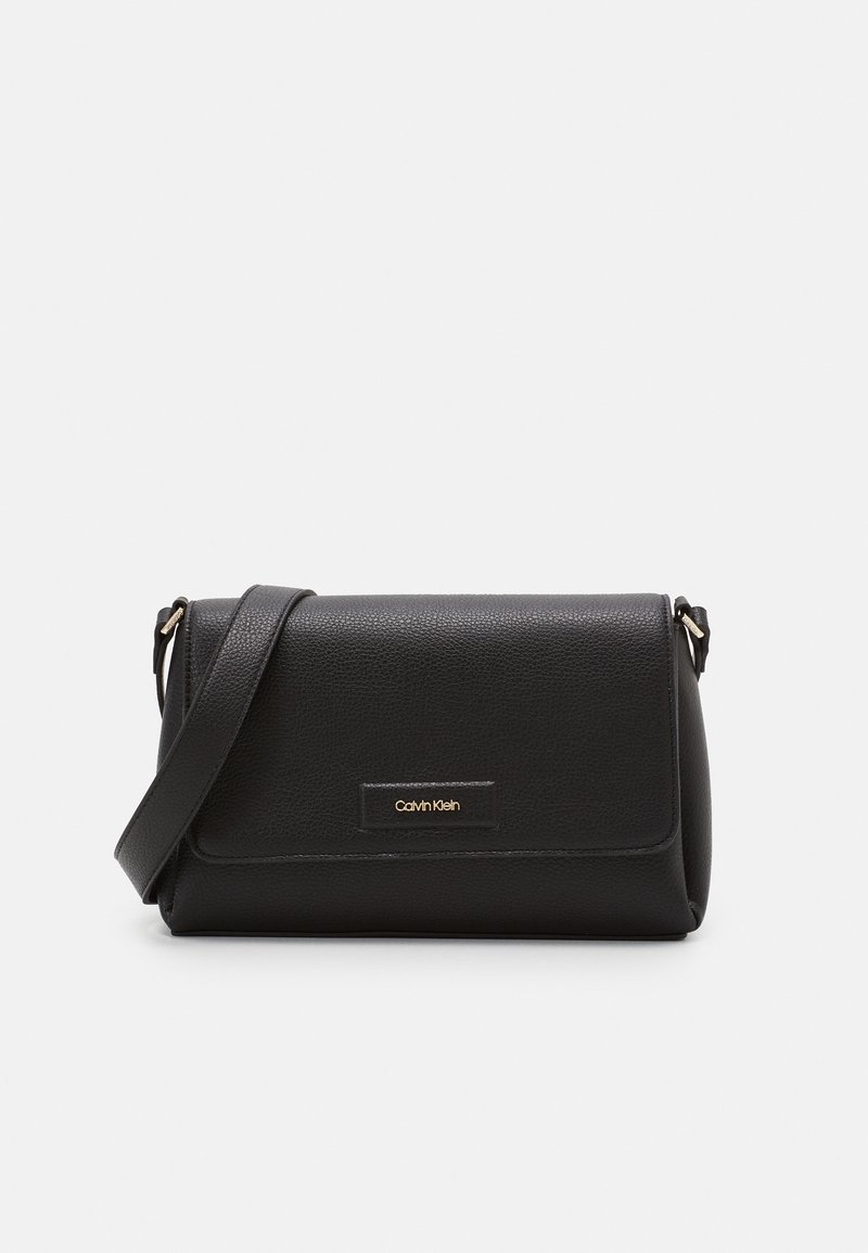 Černá kožená crossbody taška s texturovaným povrchem, sklápěcím klopou, zlatým logem a nastavitelným ramenním popruhem. Kompaktní a obdélníkový tvar.