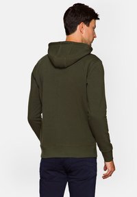 Ciemnozielona bluza z kapturem z kieszenią kangurzą, kapturem z troczkami oraz ściągaczami przy mankietach i u dołu. Materiał wydaje się miękki, o gładkiej teksturze.