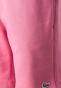 Różowe bawełniane szorty z miękką fakturą, elastycznym paskiem w talii i małym haftowanym logo po boku.