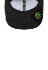 Czarna czapka z zakrzywionym daszkiem, z teksturowaną powierzchnią i zielonym okrągłym logo naszywki z boku. Wnętrze jest białe z wydrukowanymi metkami.