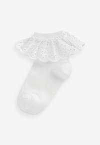 Chaussette en coton blanc avec un bord froncé en dentelle, présentant des motifs en œillet et une texture lisse sur la partie du pied.