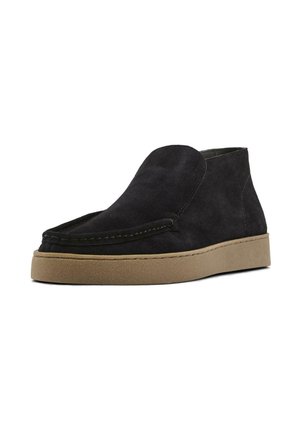Black suede ankle boots with a rounded toe, stitched detailing, and a tan rubber sole. Smooth texture with a minimalist design.