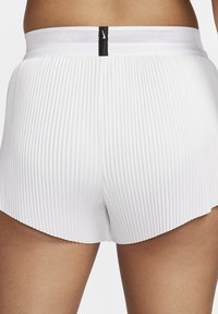 Baltos sportinės kelnės su klostėmis ir juodu elastingu juosmeniu, ant kurio yra logotipo žymė. Kelnės turi užapvalintą apačią ir tekstūruotą paviršių.