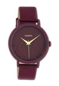 Montre en silicone bordeaux avec un cadran bordeaux texturé présentant des gravures botaniques, des aiguilles des heures et des minutes dorées, et une finition mate.