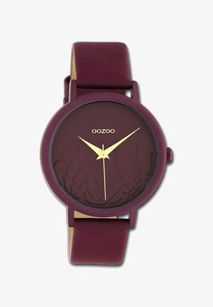 Montre en silicone bordeaux avec un cadran bordeaux texturé présentant des gravures botaniques, des aiguilles des heures et des minutes dorées, et une finition mate.
