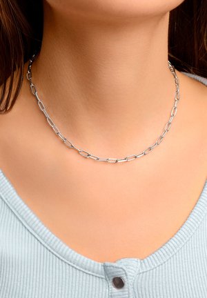Collana in argento con anelli ovali allungati. Indossata attorno al collo, mette in evidenza una finitura metallica liscia e una leggera lucentezza.