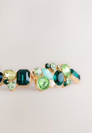 Gold-toned bracelet adorned with various green and blue gemstones in pear, round, and oval cuts, featuring a mix of textures and sizes.