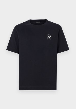 Marineblaue Baumwoll-T-Shirt mit Rundhalsausschnitt und kurzen Ärmeln. Enthält ein kleines grafisches Logo in Weiß auf der linken Brust.