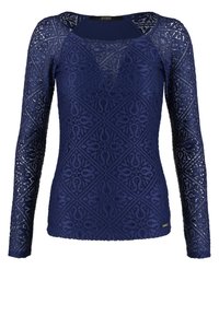 Haut à manches longues bleu marine en dentelle, présentant un motif géométrique et un décolleté en U. L'ourlet est légèrement courbé, avec une étiquette de marque.