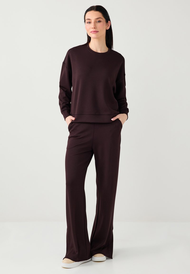 Sweat-shirt bordeaux et pantalon assorti en tissu doux. Le sweat-shirt a un col rond et des manches longues ; le pantalon est évasé avec des poches.
