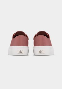 Paire de baskets basses rose poudré avec semelles plates-formes blanches et logos "cK" de Calvin Klein sur les talons arrière, vues de dos.