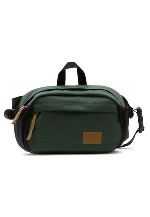 Sac banane compact vert foncé avec poche avant zippée, sangle noire réglable et écusson logo marron sur fond blanc.