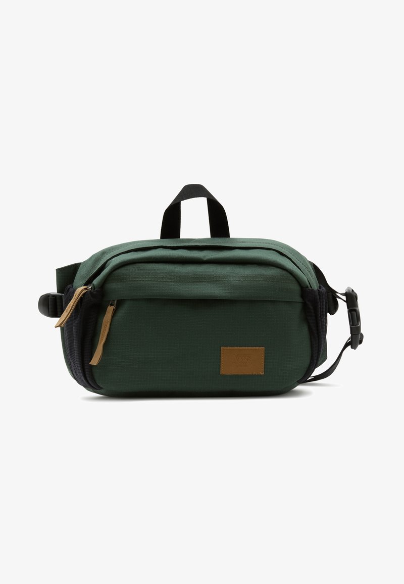 Sac banane compact vert foncé avec poche avant zippée, sangle noire réglable et écusson logo marron sur fond blanc.
