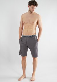 Gray shorts made of soft fabric with a blue elastic waistband featuring the logo "TOM TAILOR." Shorts have side pockets and a relaxed fit.