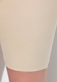 Pantaloni corti beige senza cuciture, realizzati in materiale morbido e elastico. Texture liscia con orlo dritto, progettati per comfort e versatilità.