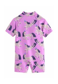 Maillot de bain à manches courtes avec un fond rose clair et un motif répétitif de licornes tachetées, rehaussé de cornes bleues et de crinières sombres.