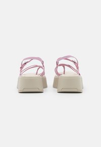 Sandálias rosa com tiras finas e sola plataforma bege chunky. As tiras são ajustáveis e t�êm um design minimalista com uma textura suave.
