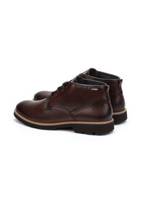 Botas de tobillo de cuero marrón con puntera redonda, costuras en contraste y forro texturizado. Cuentan con una suela de goma duradera para mayor tracción.